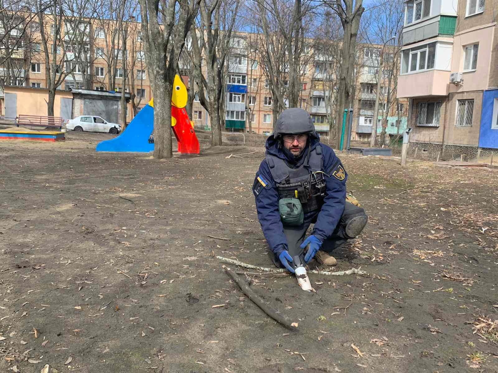 Ukrainian deminer poses with unexploded cluster bomb in Kharkiv