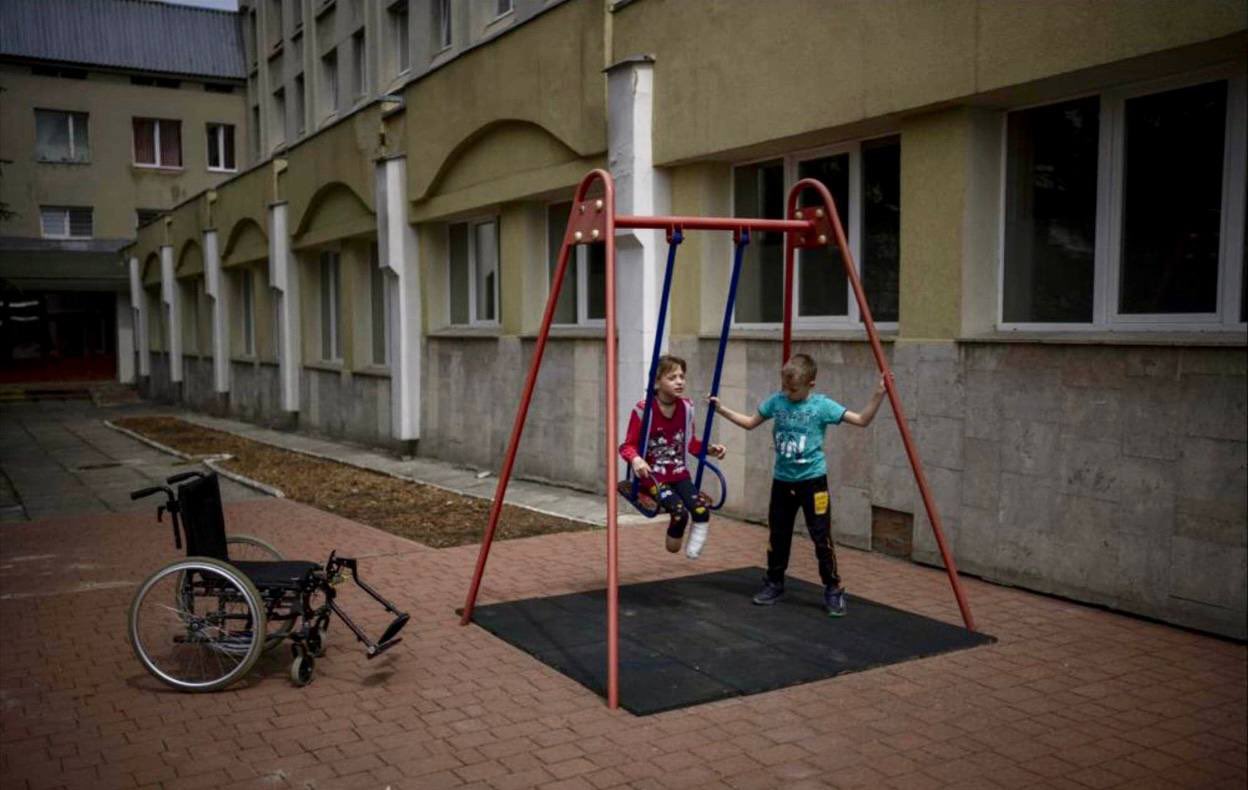 Brother pushes sister on swing outside Lviv hospital