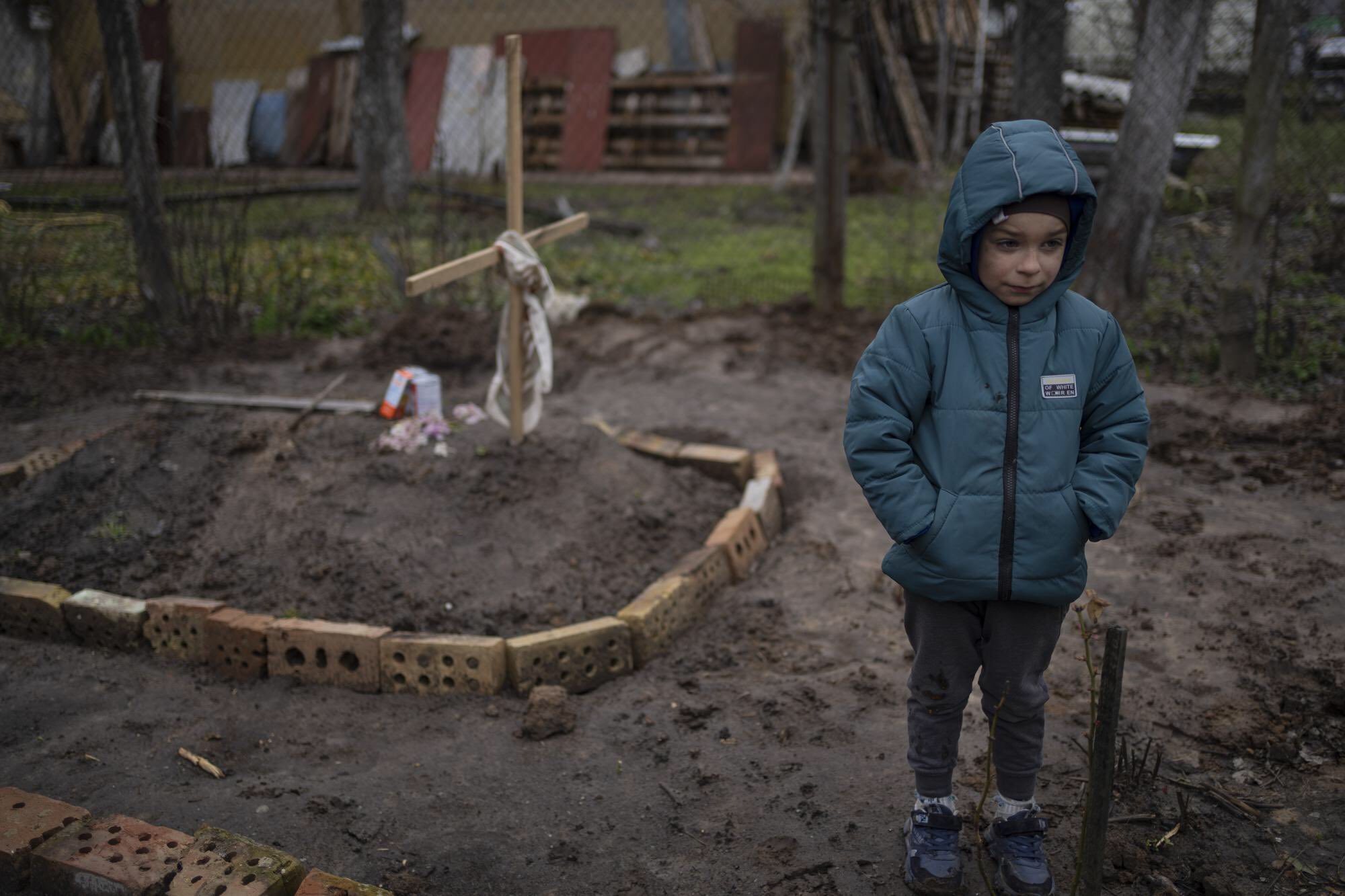 6-year-old Vlad Tanyuk stands near mother’s grave in Kyiv courtyard