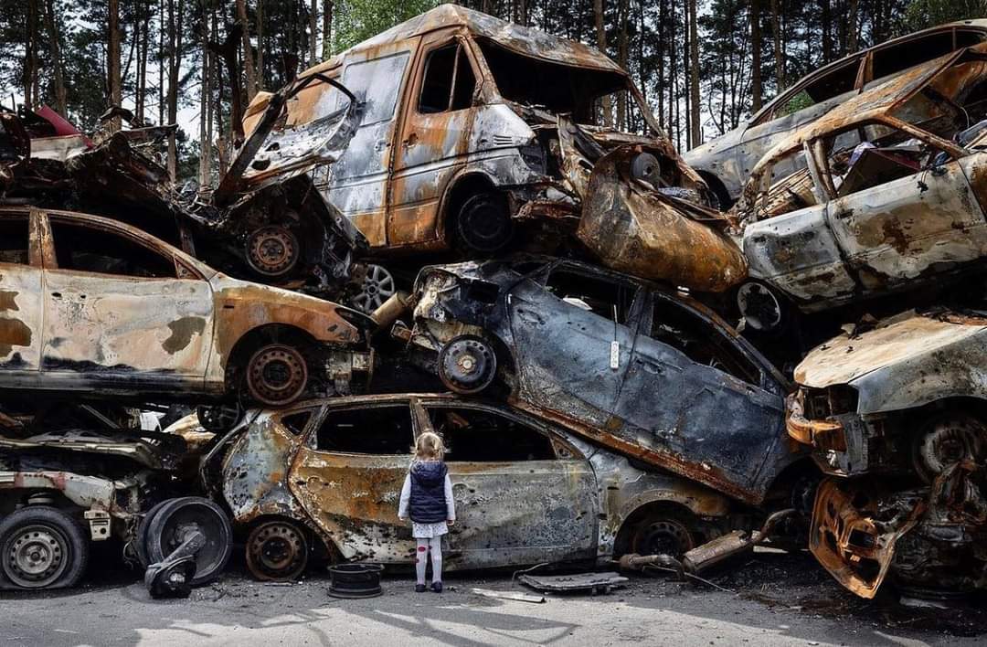 Ukrainian girl staring at car cemetery in Irpin