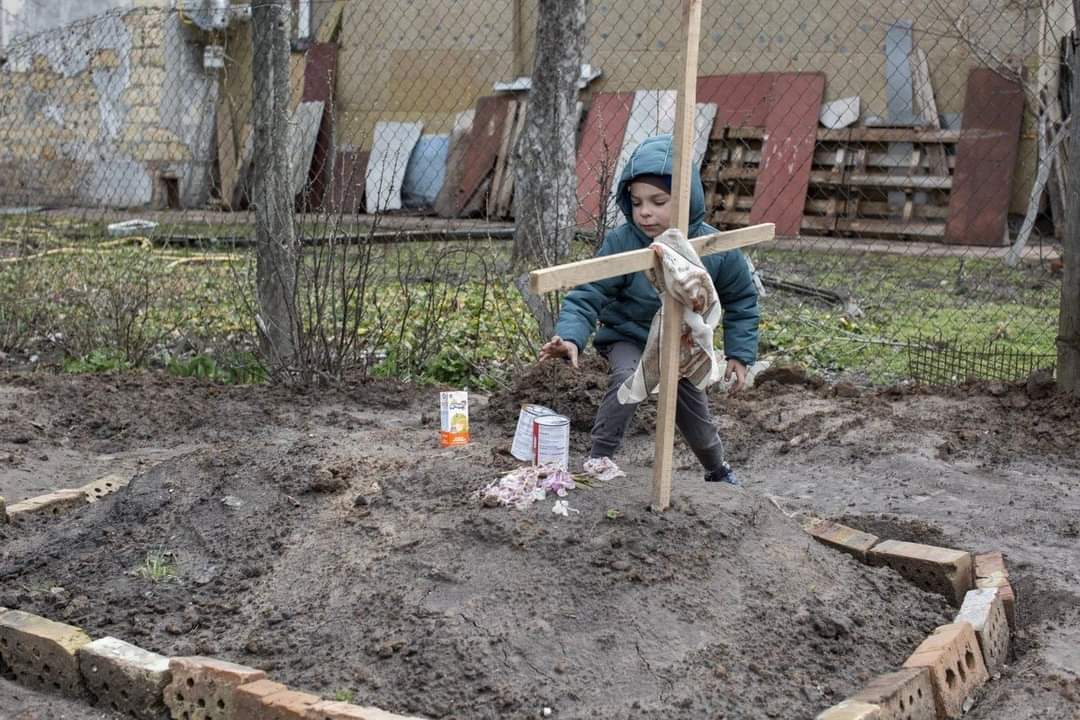 Boy brings food to mother’s grave in Bucha