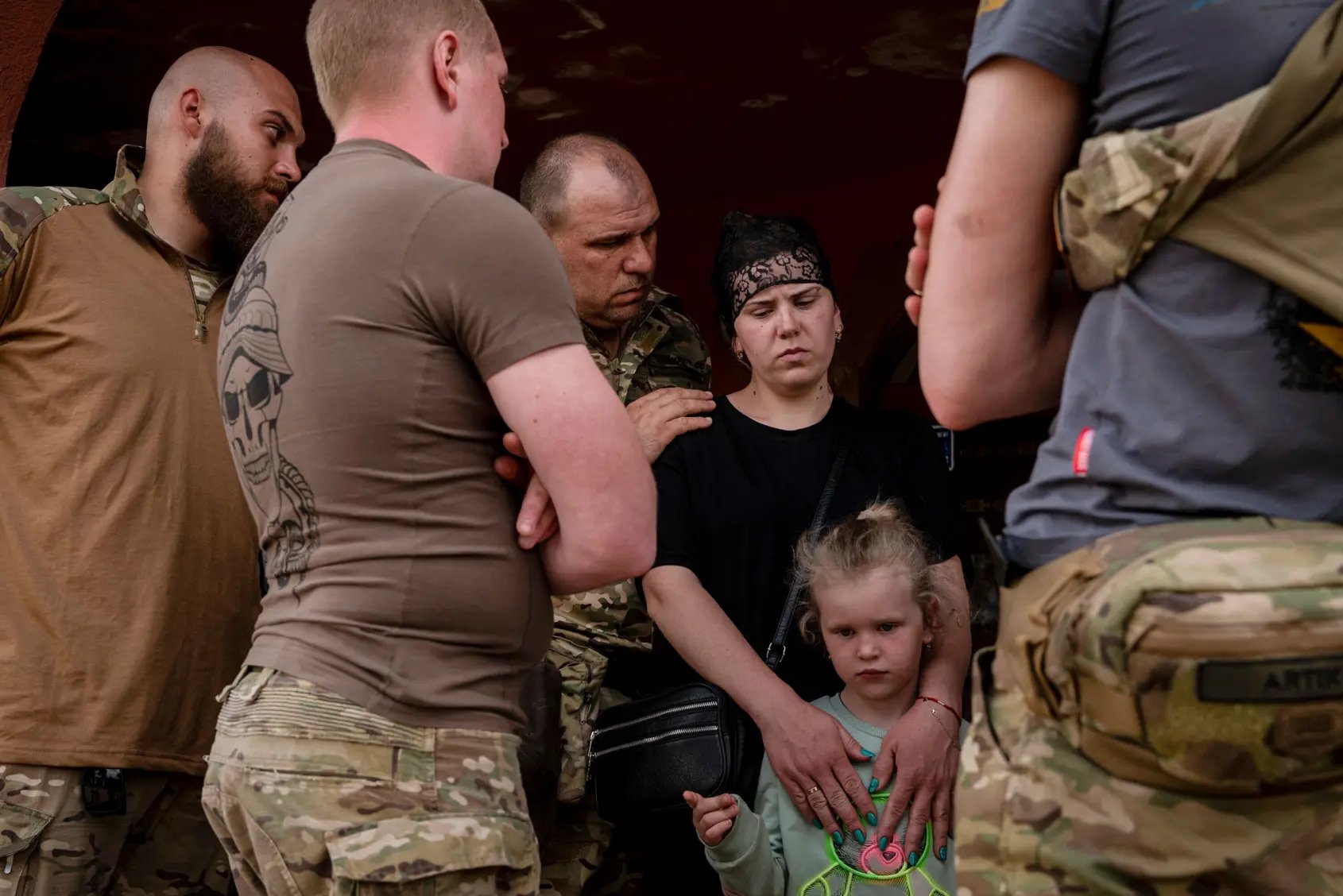Ukrainian soldiers comfort widow and daughter after funeral