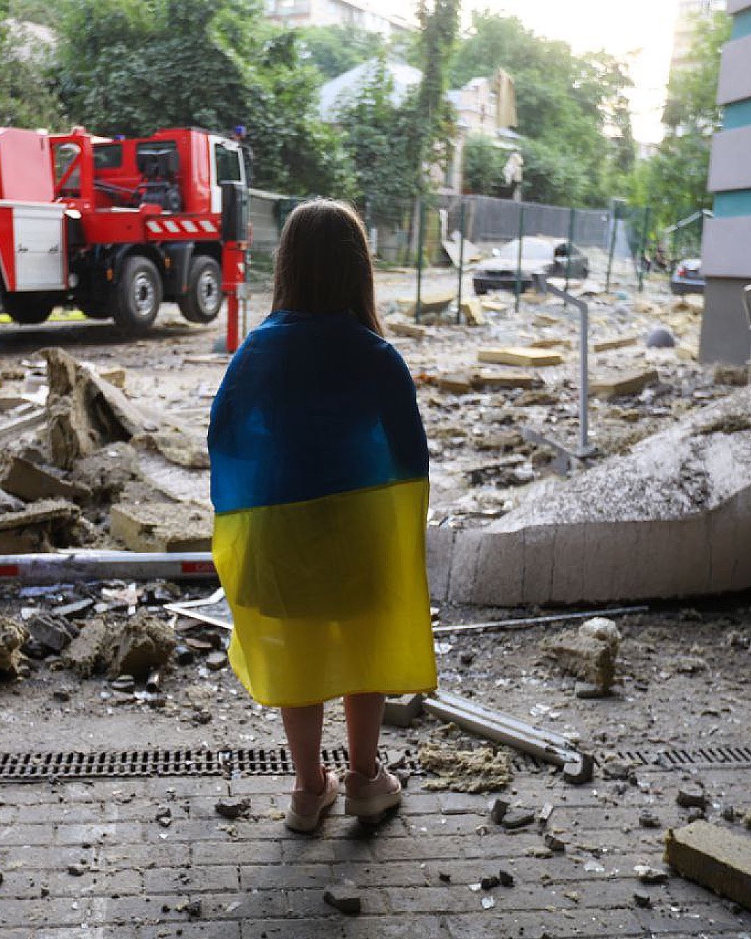 A little girl with the Ukrainian flag near a damaged house in Kyiv (translated)